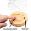 A finger is pressing a button on a wooden base of a lamp, with text indicating ease of use and secure fit. Produktbild-Vorschau