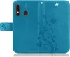 A blue flip cover for a Huawei P30 Lite phone, decorated with a floral and butterfly pattern. Produktbild-Vorschau