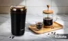 A coffee grinder and French press on a marble countertop. Podgląd zdjęcia produktu
