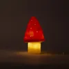 A red mushroom-shaped lamp glows with a warm yellow light from its base. Produktbild-Vorschau