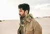 A man in a desert landscape wearing a jacket and scarf. Produktbild-Vorschau