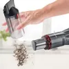 A hand is shown emptying a handheld vacuum cleaner's dustbin. Produktbild-Vorschau