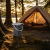 A camping toilet bucket is placed on the ground in front of a tent at a campsite. Anteprima dell’immagine prodotto
