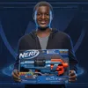 A young boy is holding a Nerf Elite 2.0 Commander RD-6 blaster box in front of a blue, futuristic background. Anteprima dell’immagine prodotto