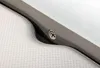 A close-up view of a textured white surface next to a gray plastic edge with a metallic circular emblem. Voir les images du produit