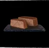 Two rectangular portions of a brown, dense food product are presented on a dark gray slate. Produktbild-Vorschau