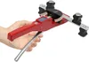 A hand holding a red pipe bender with copper pipes inserted. Náhled obrázku produktu