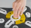 A hand is shown interacting with a dog puzzle toy, demonstrating how to use it. Produktbild-Vorschau