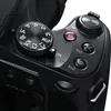A close-up view of the top and side controls of a black digital camera. Produktbild-Vorschau