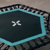 A close-up view of a hexagonal fitness trampoline mat with a teal border and a white logo. Voir les images du produit