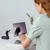 A woman is working on a laptop at a desk, with a small fan and a book on the desk. Anteprima dell’immagine prodotto