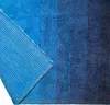 A close-up, angled view of a blue rug, showing both the textured top and the woven backing. Podgląd zdjęcia produktu