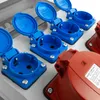 A close-up view of several industrial electrical outlets, some blue and some red, mounted on a white panel. Náhled obrázku produktu