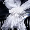 Große weiße Rosenblüten mit Organza-Schleifen als Autoschmuck auf einem Kühlergrill befestigt. Produktbild-Vorschau
