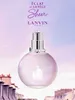 A perfume bottle is shown against a soft, gradient sky background, with rooftops of buildings visible at the bottom. Podgląd zdjęcia produktu