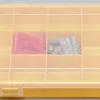 A yellow storage box with multiple compartments, containing red and gray wall plugs. Produktbild-Vorschau