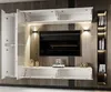 A modern living room wall unit with a television and integrated shelving, illuminated by LED lighting. Produktbild-Vorschau