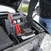 A person is using a jump starter to start a car in snowy weather. Produktbild-Vorschau