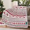 A Christmas-themed blanket with reindeer and snowflake patterns is draped over a couch next to a decorated Christmas tree. Produktbild-Vorschau