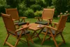A wooden garden furniture set with cushions, a drink, and a cup of coffee on a table, set on a grassy lawn with greenery in the background. Produktbild-Vorschau