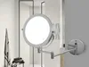A lighted makeup mirror mounted on a wall in a bathroom. Produktbild-Vorschau