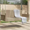 A beige rattan hanging bench with a white blanket draped over it, situated on a wooden deck with a wooden fence and greenery in the background. Náhled obrázku produktu