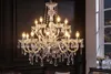 A crystal chandelier hangs in a dimly lit room, with a window showing a city view at night. Náhled obrázku produktu