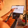 A person is using an exercise bike with a digital display. Produktbild-Vorschau