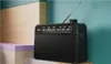 A black Philips radio is placed on a multi-colored shelf against a teal background. Voir les images du produit