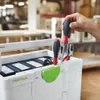 A person's hand is holding a screwdriver, placing it into a white Festool Systainer toolbox. Other tools are visible inside the toolbox. Anteprima dell’immagine prodotto