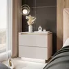 A bedroom scene featuring a nightstand with decorative items and a bed in the background. Produktbild-Vorschau