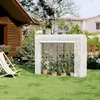 A white greenhouse with plants inside, set up on a green lawn next to a wooden house and a lounge chair. Náhľad obrázku produktu