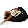 A young boy is playing a video game while sitting on a large black beanbag chair. Podgląd zdjęcia produktu