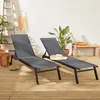 Two grey sun loungers are set up on a wooden deck next to a white wall, with plants and a small wooden bench in the background. Produktbild-Vorschau