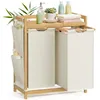 A bamboo laundry basket with two compartments and a shelf, displayed on a white background with some bathroom accessories. Náhled obrázku produktu