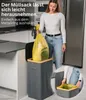 A woman is shown removing a yellow trash bag from a gray trash can with a wooden rim in a kitchen setting. Náhľad obrázku produktu