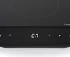A close-up of a black induction cooktop with a digital display. Voir les images du produit