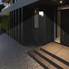A modern house exterior at night, with a lit LED outdoor light illuminating the entrance steps and walkway. Produktbild-Vorschau