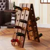 A wooden wine rack filled with wine bottles is placed on a wooden floor in a room with a leather armchair and a side table. Produktbild-Vorschau
