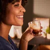 A woman is smiling and holding a glass of coffee. Produktbild-Vorschau