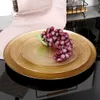 A close-up shot of gold-colored dessert plates stacked on top of each other, with a bunch of red grapes placed on the top plate. Podgląd zdjęcia produktu