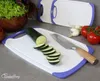 A kitchen scene with sliced zucchini on a cutting board, a knife, tomatoes, garlic, and a bowl of lettuce. Anteprima dell’immagine prodotto