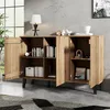 A wooden sideboard with open doors, displaying shelves with books and decorative items, in a room with a concrete wall and a large window. Anteprima dell’immagine prodotto