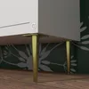 Close-up of the bottom of a white cabinet with gold metal legs. Produktbild-Vorschau
