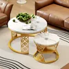 A living room scene with a brown leather sofa and two round coffee tables with marble tops and gold metal legs. Produktbild-Vorschau