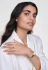 A woman wearing a white blazer and jewelry, including a gold watch, ring, and earrings. Produktbild-Vorschau