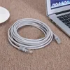A coiled gray Ethernet cable is placed on a textured brown carpet next to a white plate and a portion of a laptop. Náhled obrázku produktu