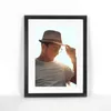 A man wearing a hat and sunglasses, holding the brim of his hat, with the sun shining behind him. Anteprima dell’immagine prodotto