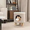 A cat is sitting inside a beige cat house with scratching posts, placed on a rug in a living room. Voir les images du produit