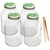 Four glass jars with pickle-themed lids and a pair of wooden tongs. Podgląd zdjęcia produktu
